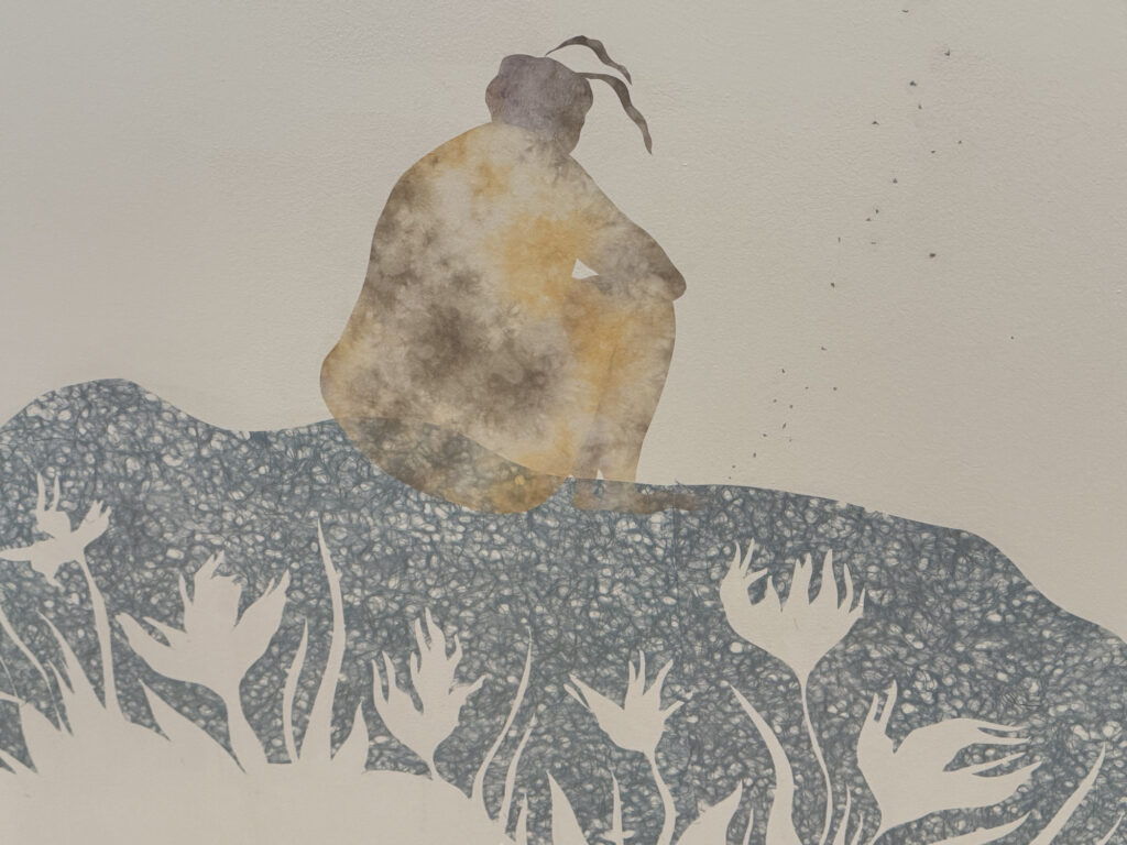 A woman sits by the water pondering while wildflowers blow in Junli Song's Garden of Memory at MCLA's Gallery 51. Press photo by Kate Abbott