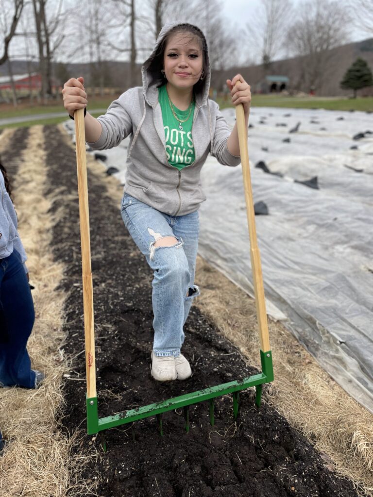 A teen farm apprentice works in the fields at seeding and planting time. Press photo courtesy of Roots Rising